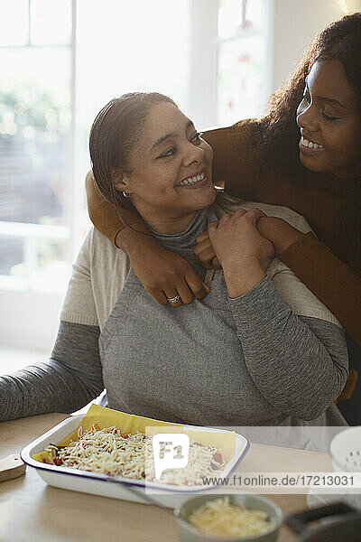 Glückliche liebevolle Mutter und Tochter machen hausgemachte Lasagne