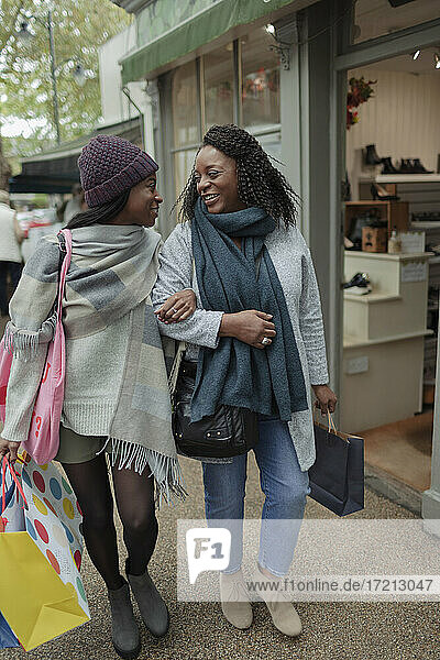 Mutter und Tochter mit Einkaufstaschen gehen Arm in Arm
