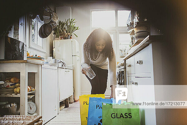 Frau sortiert Recycling in Säcken auf dem Küchenboden