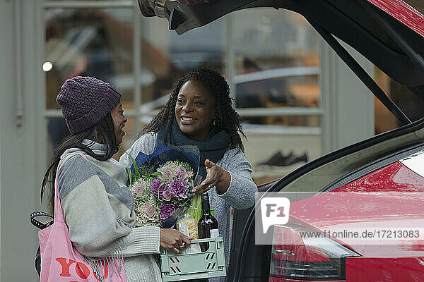 Mutter und Tochter laden Lebensmittel in den hinteren Teil des Autos vor dem Geschäft