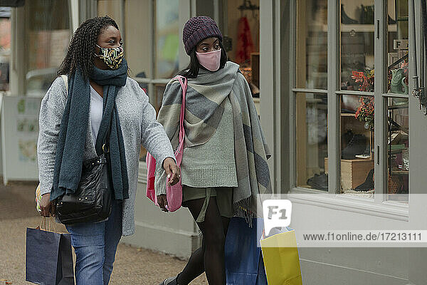 Mutter und Tochter in Gesichtsmasken mit Einkaufstüten