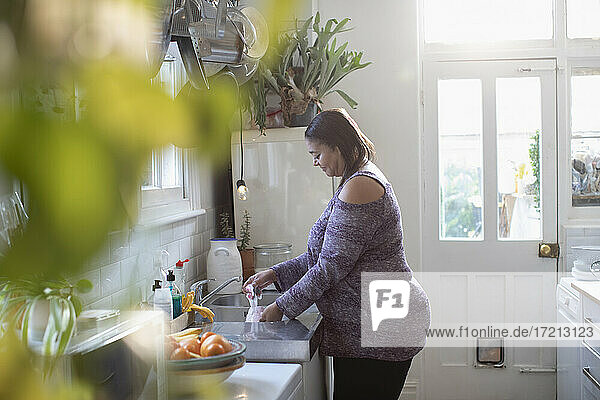 Frau macht Geschirr an der Spüle