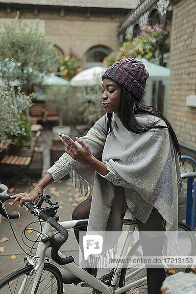 Junge Frau mit Smartphone auf dem Fahrrad