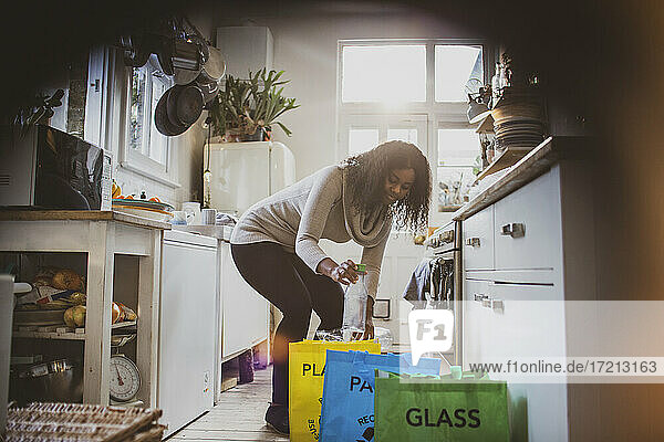 Junge Frau sortiert Recycling auf dem Küchenboden