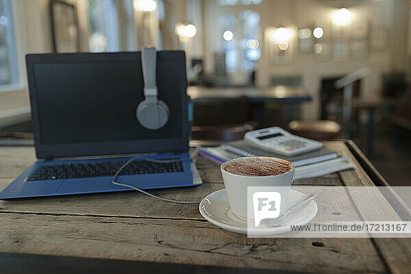 Cappuccino auf dem Tisch neben dem Laptop im Cafe