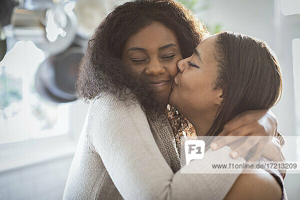 Happy mother and daughter hugging and kissing