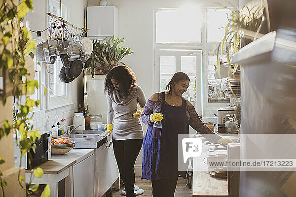 Mutter und Tochter in Gummihandschuhen beim Reinigen der Küche