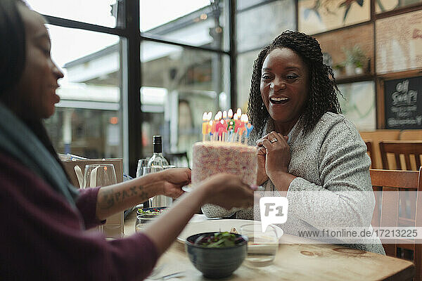 Glückliche Mutter und Tochter feiern Geburtstag mit Kuchen im Cafe