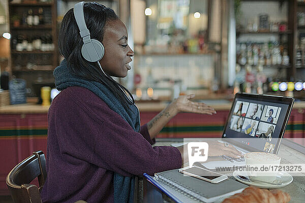 Junge Frau mit Kopfhörer Video-Chat mit Kollegen im Café