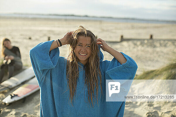 Portrait happy young female surfer with wet hair on sunny beach