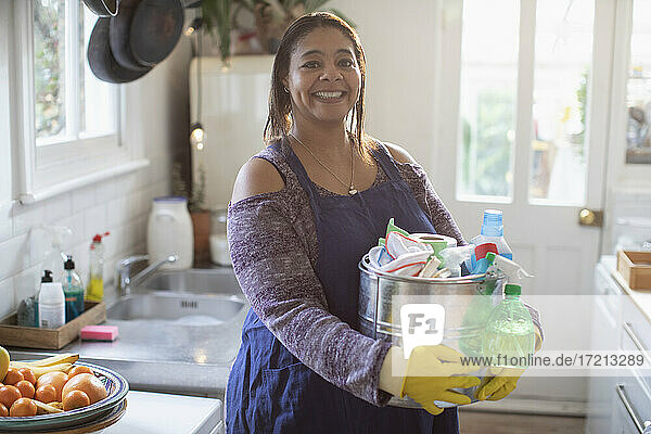 Porträt lächelnde Frau mit Reinigungsmitteln in der Küche