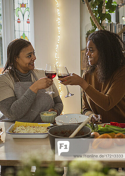 Mutter und Tochter kochen und trinken Wein zu Hause