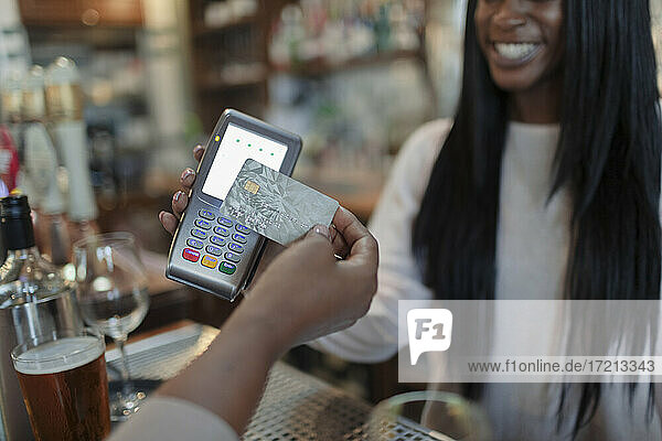 Close up Kunde zahlen weiblichen Barkeeper mit Smartcard in der Kneipe