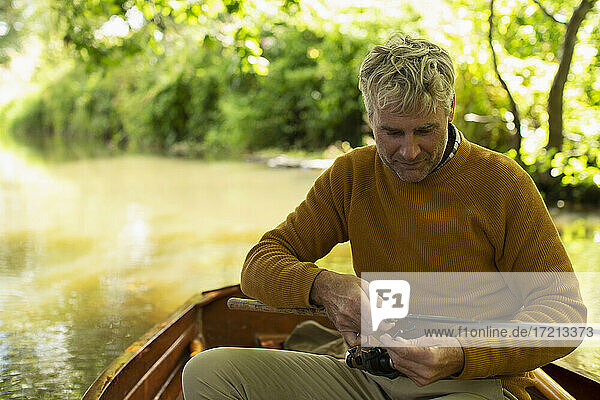 Mann bereitet Fliegenfischerleine in Boot auf Fluss vor
