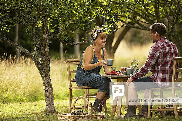 Ehepaar macht eine Pause von der Gartenarbeit am Tisch im Obstgarten