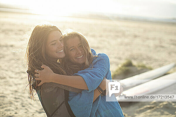 Porträt glücklich junge weibliche Surfer umarmen auf sonnigen Strand