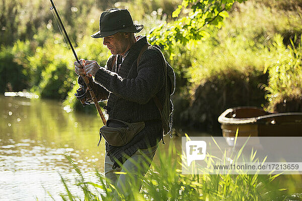 Man preparing fly fishing line at sunny river