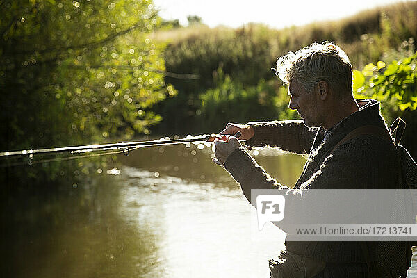 Man preparing fly fishing pole at sunny river
