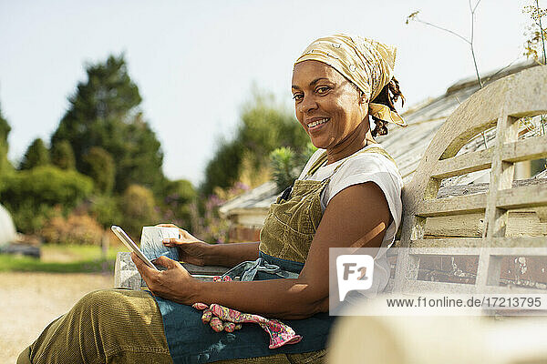 Porträt glückliche weibliche Gartenladenbesitzerin macht Kaffeepause auf Bank