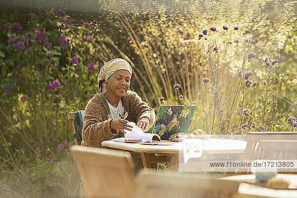 Frau arbeitet am Laptop am idyllischen Gartencafé Tisch
