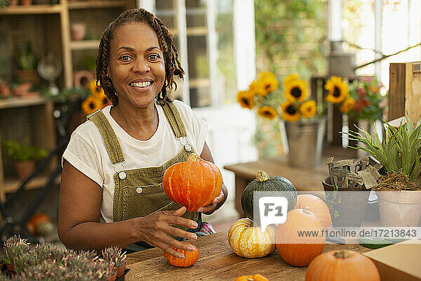 Porträt glücklich weiblichen Florist arrangieren Herbst Kürbisse im Laden