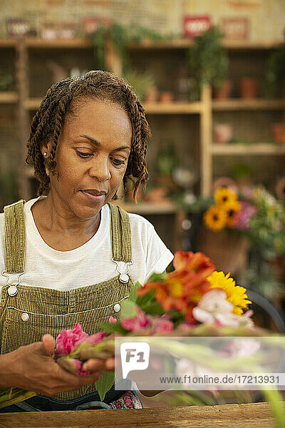 Weiblicher Florist arrangiert Blumen im Geschäft