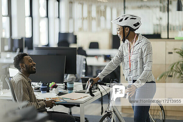 Geschäftsfrau mit Fahrrad im Gespräch mit Geschäftsmann im Büro