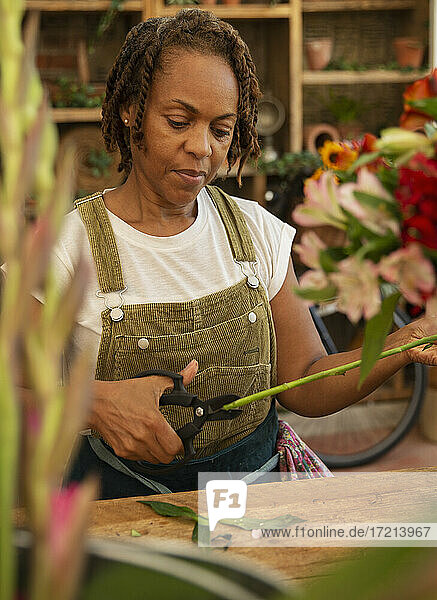 Weiblicher Florist trimmt Blumenstängel im Geschäft