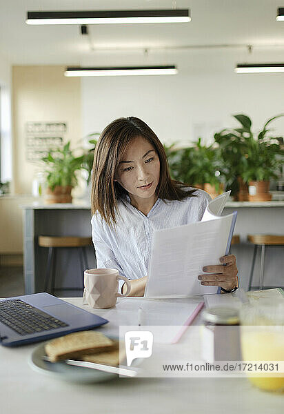 Businesswoman reviewing paperwork in office lounge