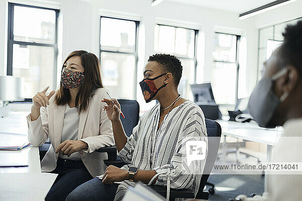 Geschäftsleute mit Gesichtsmasken treffen sich im Büro