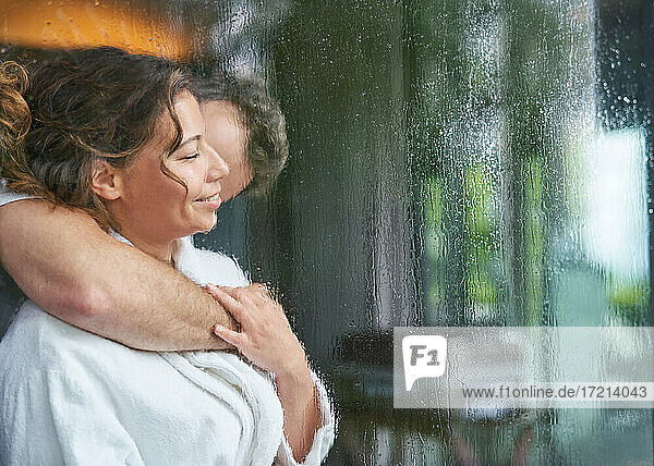 Zärtliches romantisches Paar  das sich am regnerischen Fenster umarmt