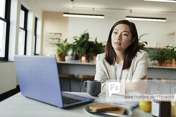 Thoughtful businesswoman working at laptop in office