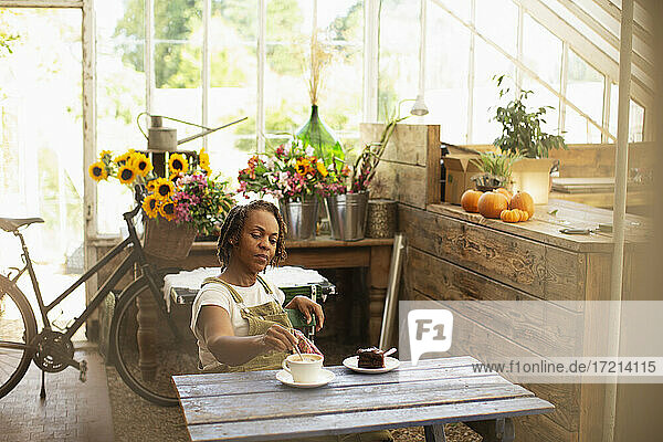 Weibliche Floristin genießt Kaffeepause am Tisch im Blumenladen