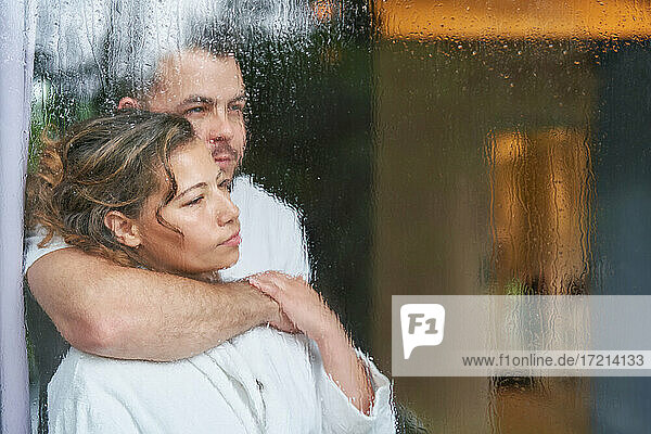 Serene zärtliches Paar umarmt bei regnerischen Fenster