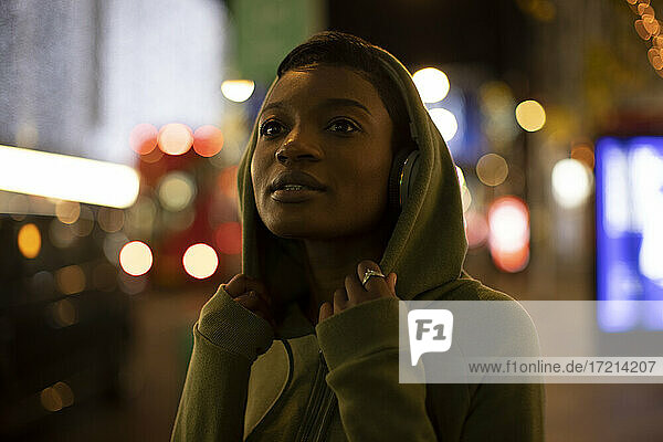 Junge Frau in Kapuze auf Stadt Bürgersteig in der Nacht
