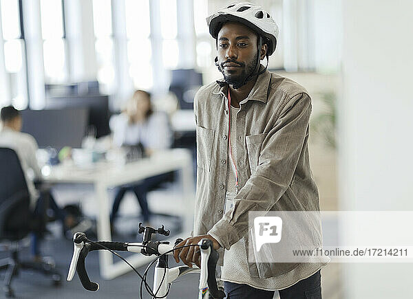 Geschäftsmann zu Fuß Fahrrad im Büro