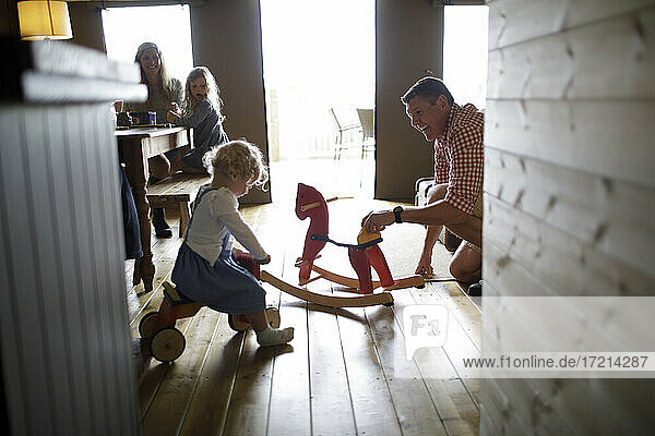 Familie mit Schaukelpferd und Spielzeug in der Hütte