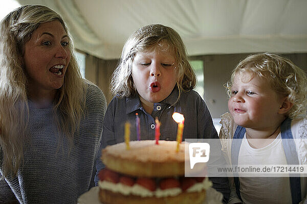 Happy Boy Ausblasen Geburtstagskuchen Kerzen mit Familie