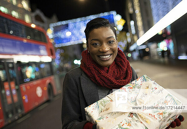 Porträt junge Frau mit Weihnachtsgeschenk auf Stadt Bürgersteig in der Nacht