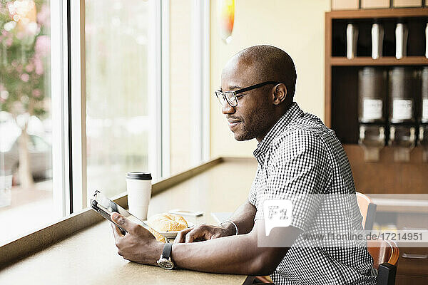 Black man using digital tablet in coffee shop