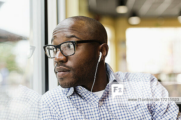 Schwarzer Mann hört Kopfhörer in einem Café