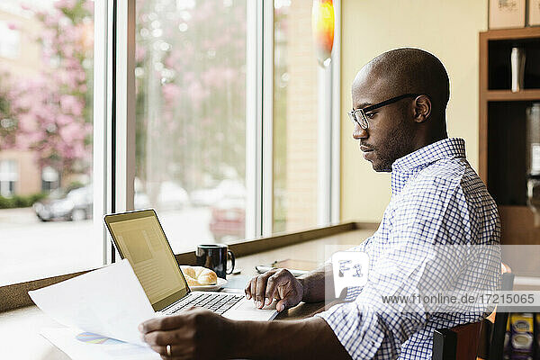 Black man using laptop in coffee shop