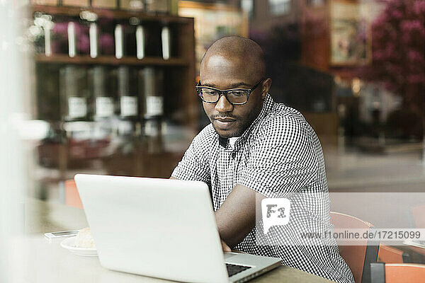 Schwarzer Mann benutzt Laptop in Café