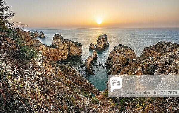 Schroffe Felsenküste mit Klippen aus Sandstein  Felsformationen im Meer  Ponta da Piedade  Morgenrot bei Sonnenaufgang  Algarve  Lagos  Portugal  Europa