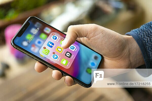 Hand hält iPhone 11 Pro mit App-Icons von Messenger Diensten und Sozialen Netzwerken  WhatsApp  Facebook  Telegram  Snapchat  Threema  Smartphone