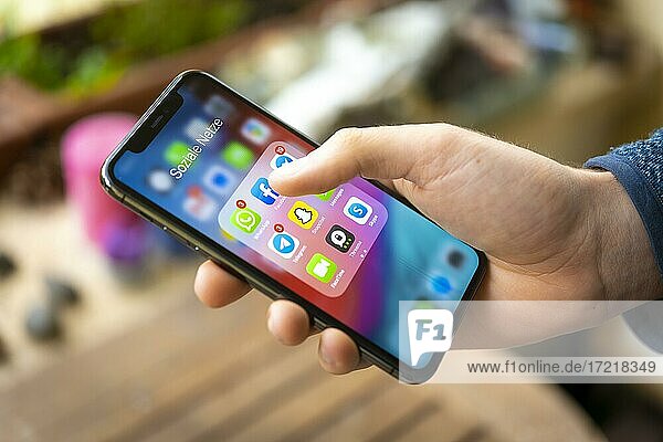 Hand hält iPhone 11 Pro mit App-Icons von Messenger Diensten und Sozialen Netzwerken  WhatsApp  Facebook  Telegram  Snapchat  Threema  Smartphone