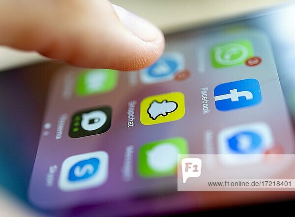 Finger tippt auf Bildschirm mit App Symbolen von Messenger-Diensten und sozialen Netzwerken  WhatsApp  Facebook  Telegram  Snapchat  Threema  iPhone 11 Pro  Smartphone