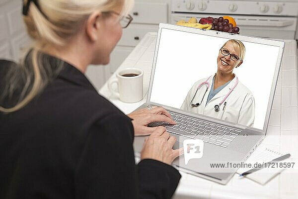 Frau in Küche mit Laptop  Online-Chat mit Krankenschwester oder Ärztin auf Bildschirm