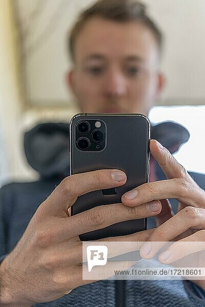 Junger Mann tippt auf  hält iPhone 11 Pro  Smartphone