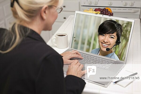 Over shoulder of woman in kitchen using laptop  online chat with nurse or doctor on screen
